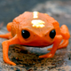 A bright orange miniaturized frog walking.